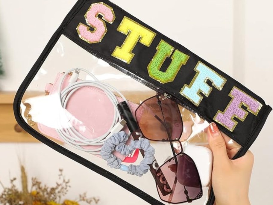 hand holding a clear zipper pouch with black accents and block letters that says STUFF