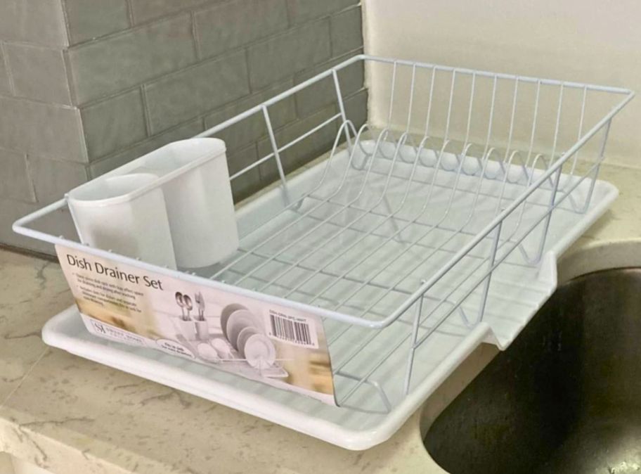 a white dish draining rack on a marble countertop next to a stainless steel sink