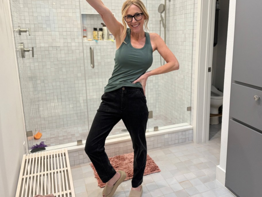 woman wearing green tank with black jeans in bathroom