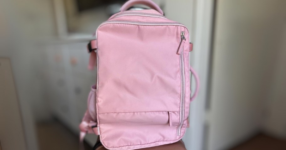 large pink travel backpack on a suitcase in a room