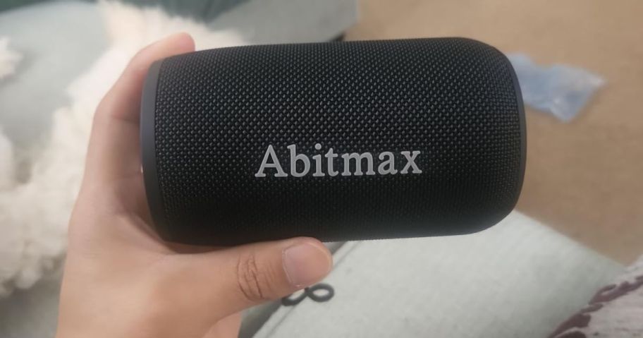 A hand holding ABitmax Bluetooth Speaker in black