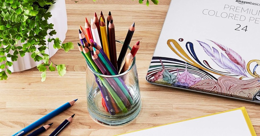 glass cup filled with colored pencils on a desk
