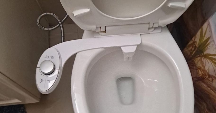 white toilet open showing slim bidet attachment on it