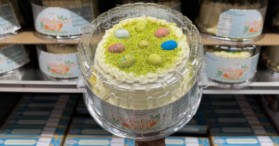 A hand holding a Bakery Street Easter Carrot Cake with Eggs on top of it
