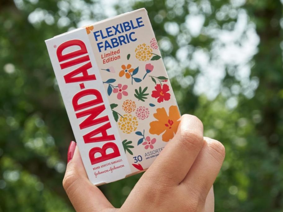 A hand holding a box of Band-Aid Flexible Fabric Wild Flowers