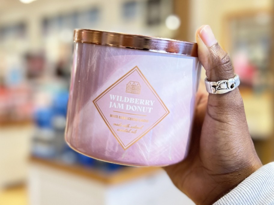 hand holding up a large pink bath & body works candle in store