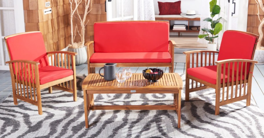 wood patio seating set with red cushions on a blue and white area rug