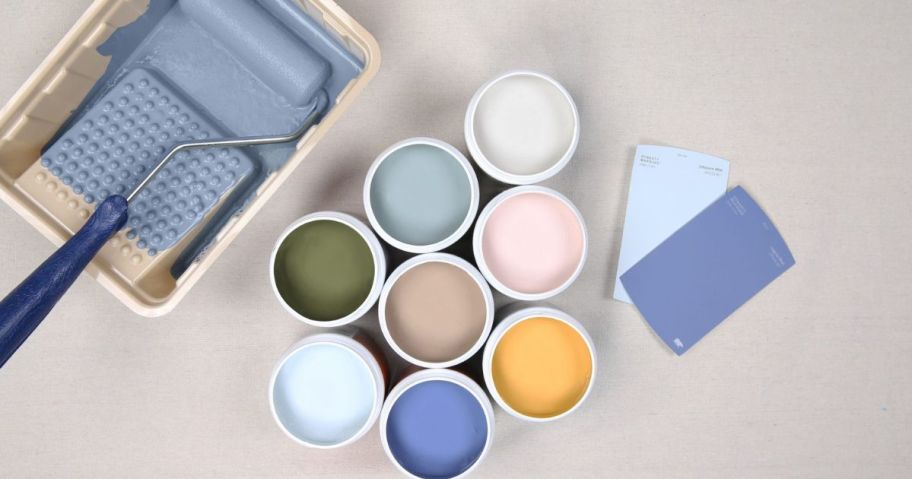 A paint roller, tray, and several Behr color samples