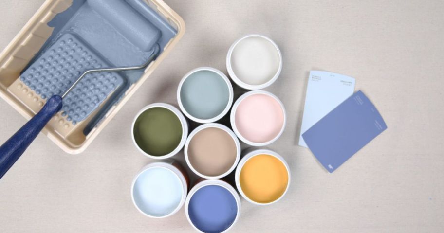 A paint roller, tray, and several Behr color samples