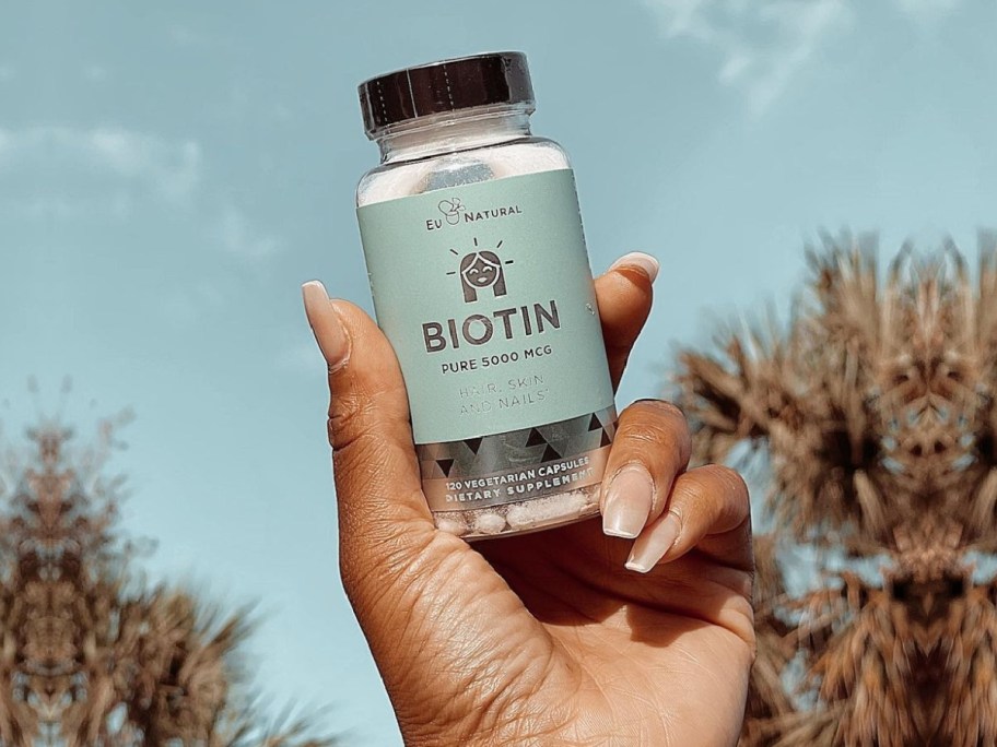 hand holding biotin pills while outside