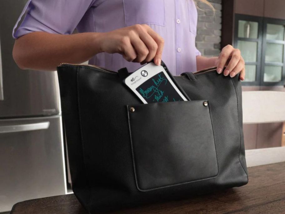 hand putting a boogie board tablet into a purse