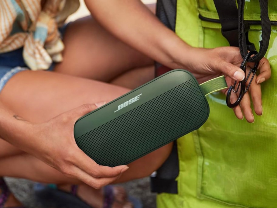 clipping a green bose wireless speaker to a backpack