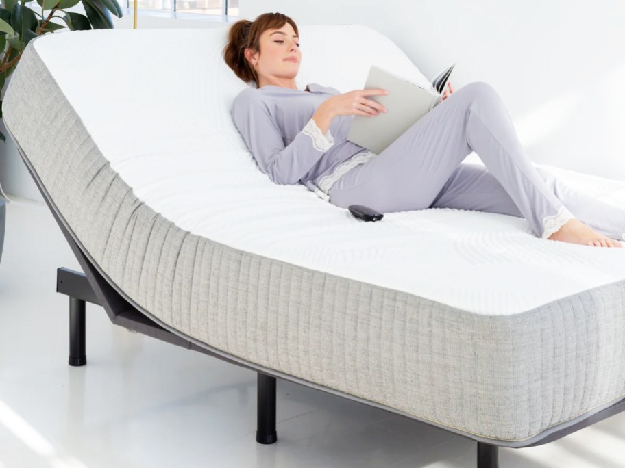 woman reading book while laying on a propped up mattress