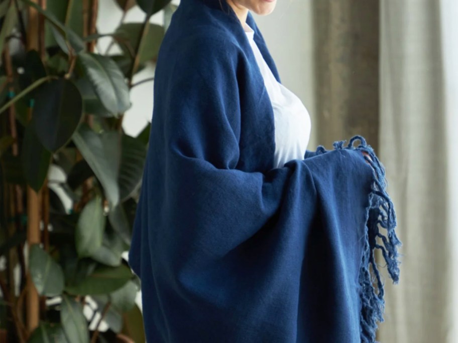 woman wrapped up in a navy blue throw blanket with fringe
