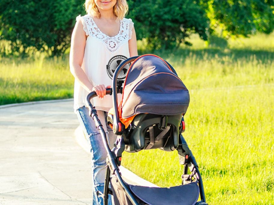 Woman pushing a baby stroller with a fan attached to it