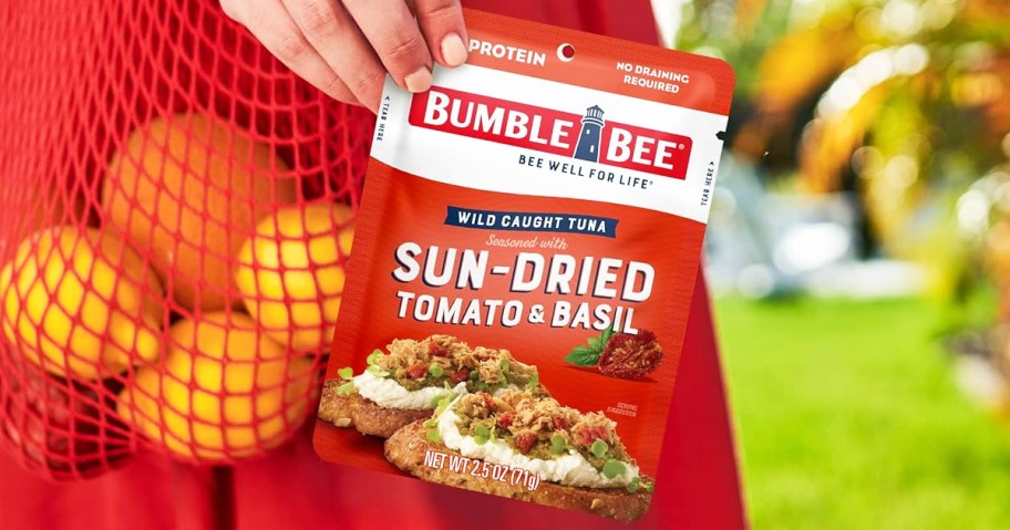 woman holding red Bumble Bee Seasoned Tuna Pouch in Sun Dried Tomato Basil flavor