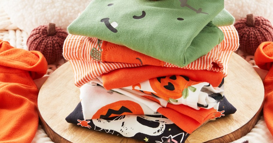 stack of folded halloween pajamas on a round wood board