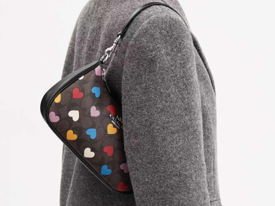 woman in grey jacket with brown purse with heart print