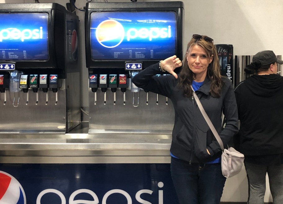 Woman giving a thumbs down sign in front of the Costco Pepsi machines