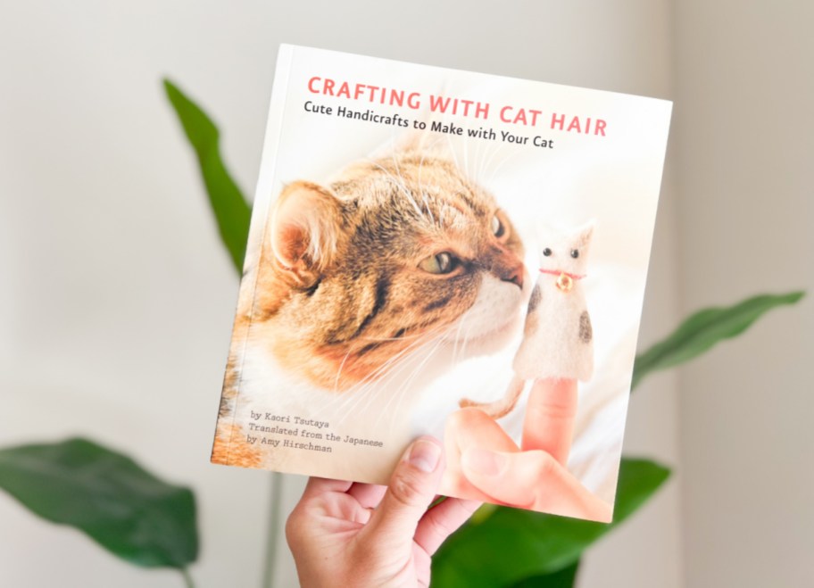 hand holding up a copy of the book Crafting with Cat Hair which has easy DIY projects that can be made with fur