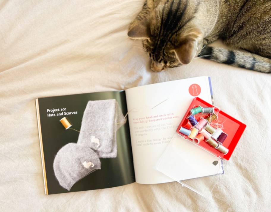 Crafting with cat hair book next to a cat and a sewing kit and opened to show an easy diy craft project