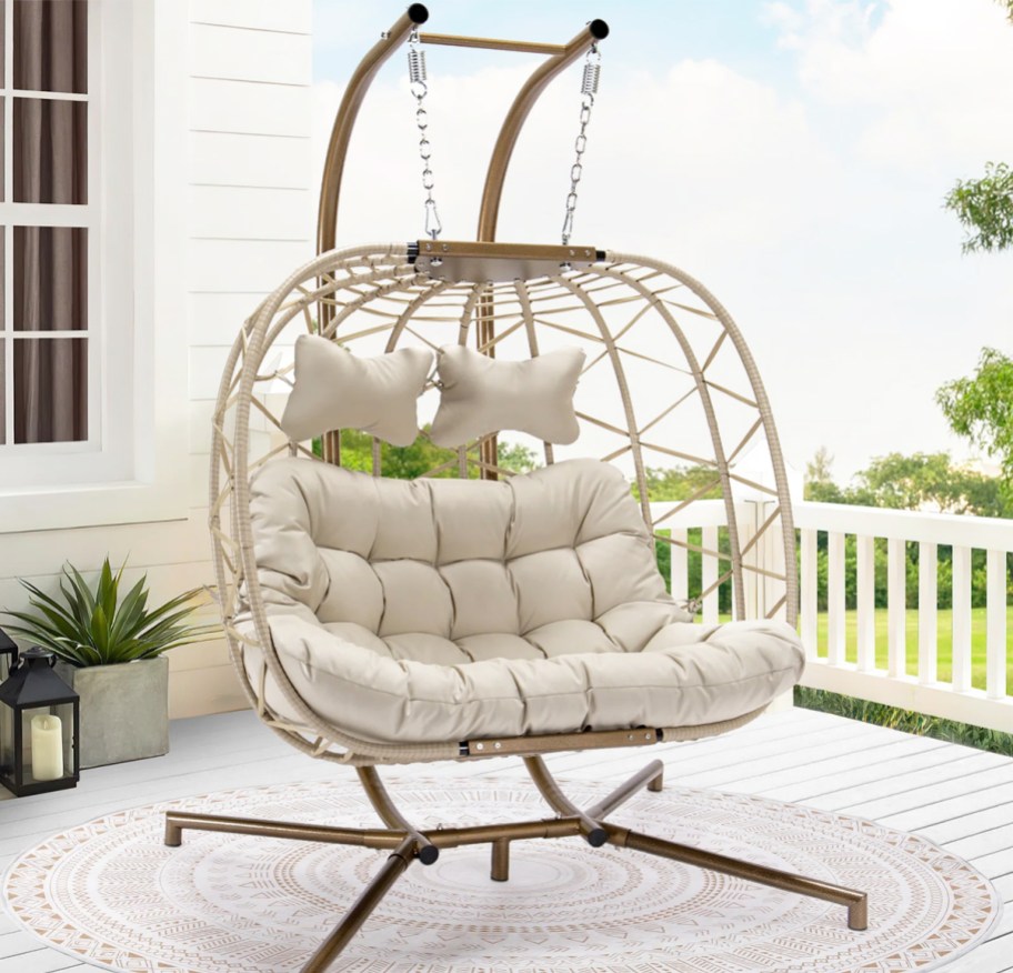 white 2-person egg chair with white cushions hanging from stand