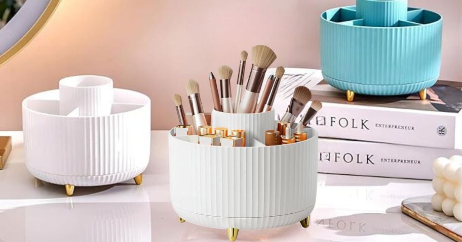 Dasiton Large Capacity Rotating Makeup Brush Organizer in White on bathroom counter with other organizers and books in the background