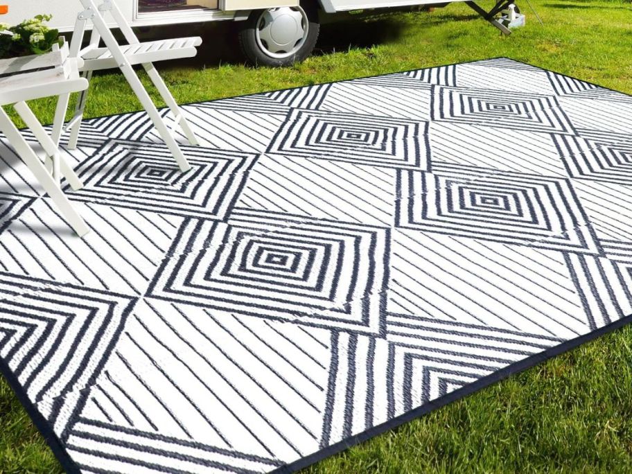 A DiiKoo Outdoor Rug Mat outside in front of a camper