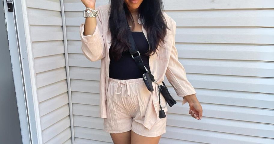 woman wearing a beige color linen top and shorts lounge set with a black tank top and crossbody bag