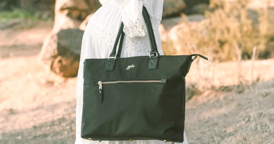 JuJuBe Evironmental Friendly Eco Tote Diaper Bag being held by a pregnant woman outside