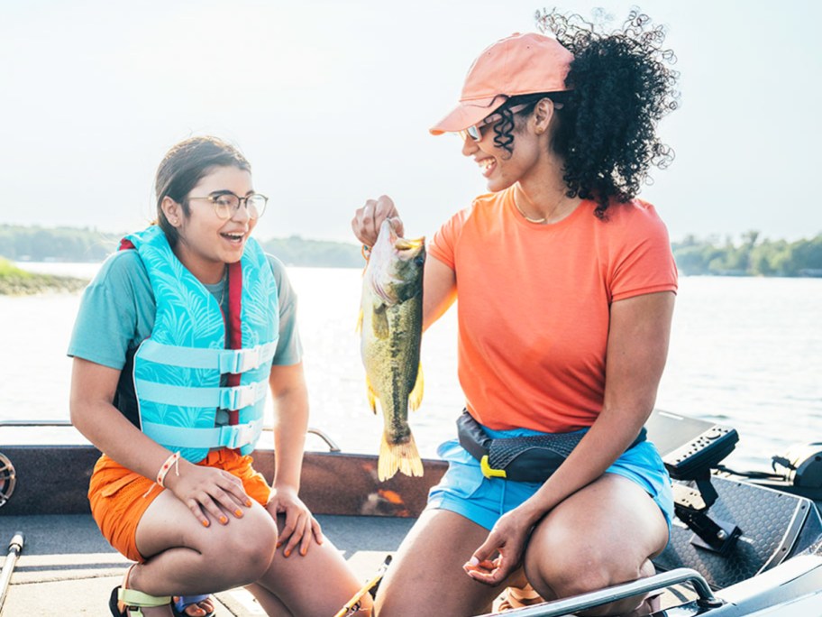 woman and girl in boat holding up fish