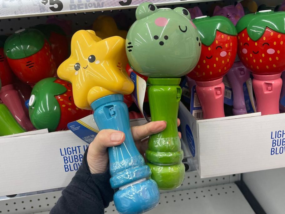Hand holding two light up bubble blower wands at Five Below