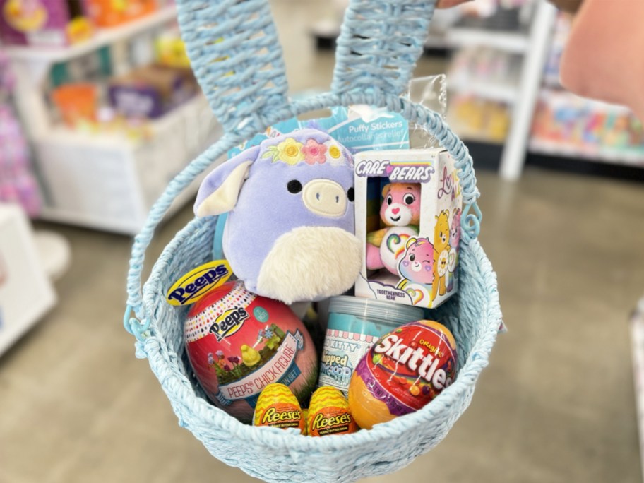 holding up blue easter basket with toys and candy inside