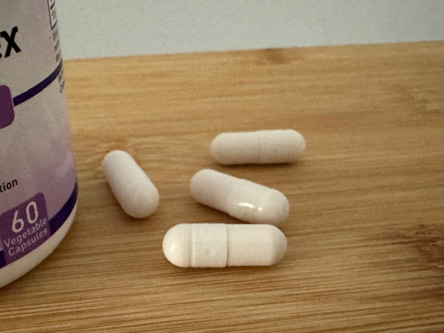 Four pills placed on a table next to pill bottle