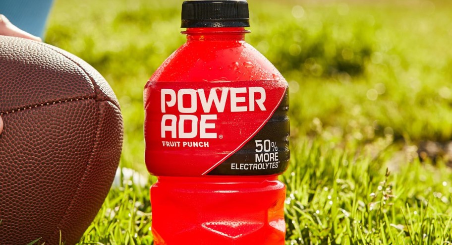 Fruit punch Powerade displayed on grass with a football next to it