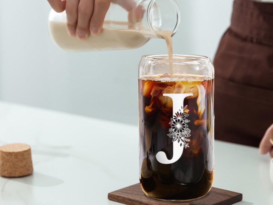 Glass cup with initals and coffee being poured into it with milk