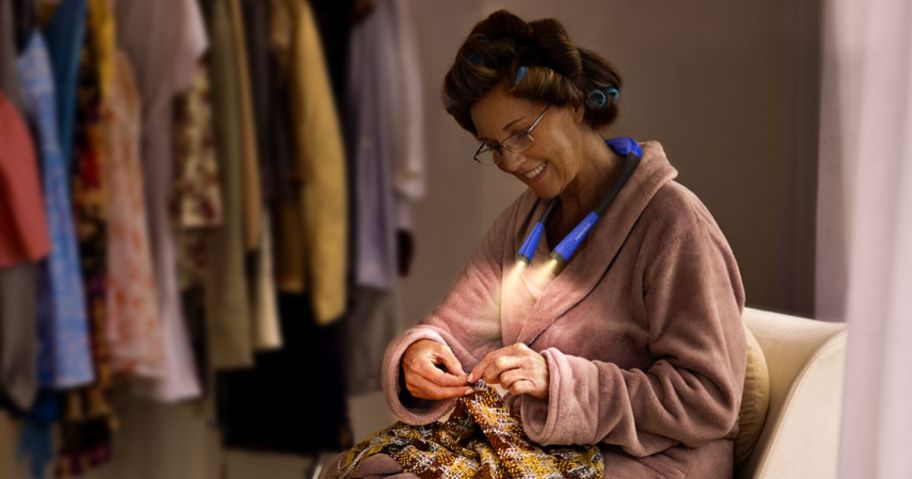 woman stitching and wearing blue neck reading light 