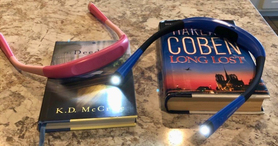 pink and blue LED neck reading lights on top of books laying on a counter