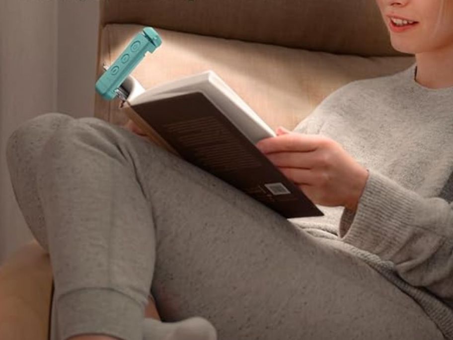 A person reading a book using a Glocusent USB Rechargeable Book Light