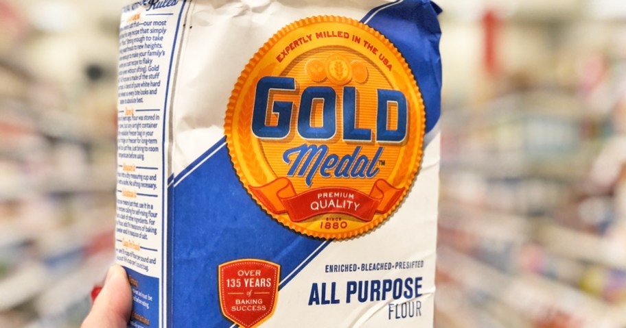 Hand holding up a bag of Gold Medal Flour in store