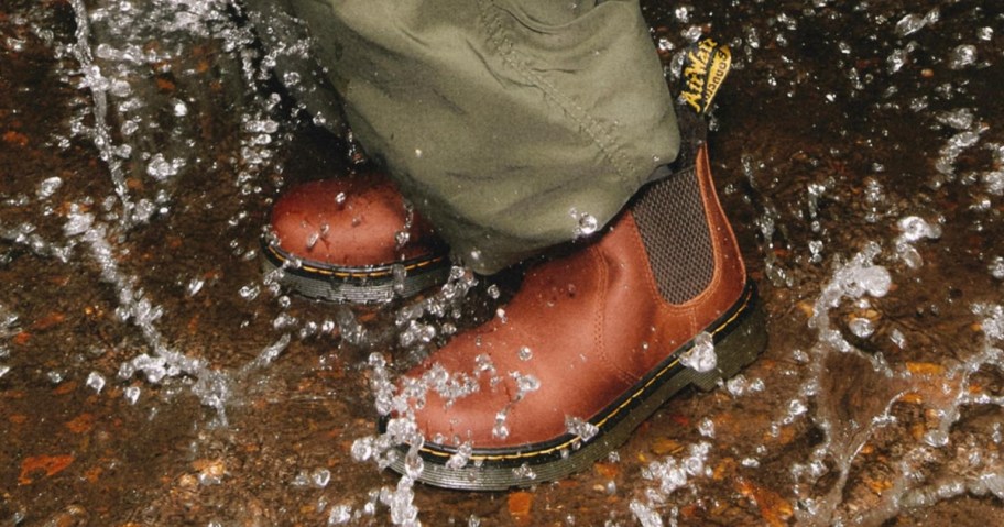 kid wearing brown Dr. Martens boots splashing in a puddle