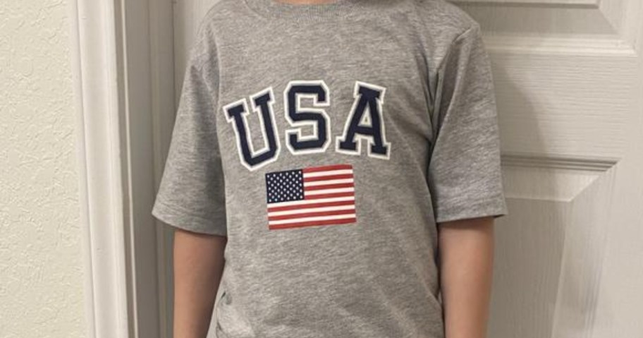 kid wearing a grey t-shirt that has "USA" and an American flag on it