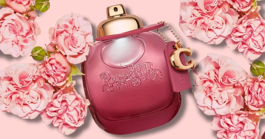 dark pink bottle of Coach perfume on a pink background surrounded by pink roses