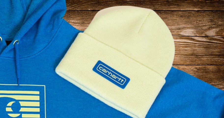 a light green Carhartt beanie laying on a blue Carhartt hoodie