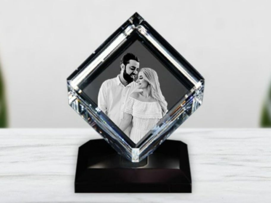 3D crystal photo cube on black stand on shelf