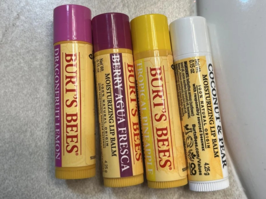 four Burt's Bees lip balms laying on a sink