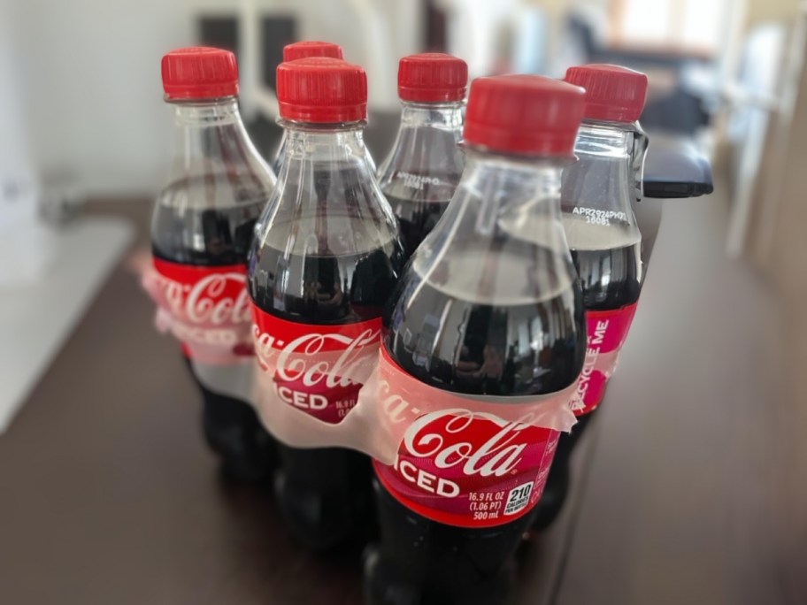 6 pack of Coca-Cola Spiced individual size bottles on a kitchen table
