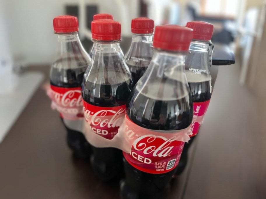 6 pack of Coca-Cola Spiced individual size bottles on a kitchen table