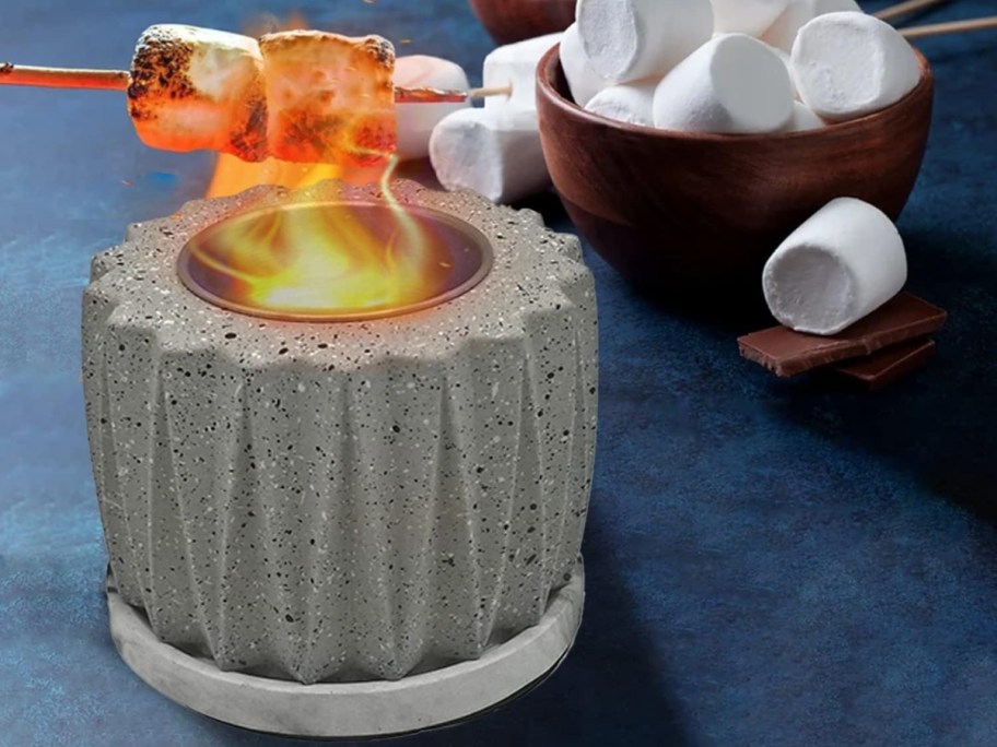 ceramic grey mini tabletop fire pit with someone roasting marshmallows on it