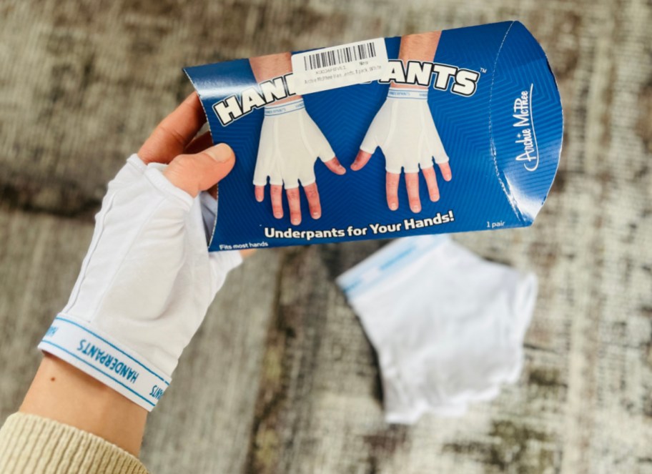 A pair of hands wearing handerpants underwear for hands and holding up the package